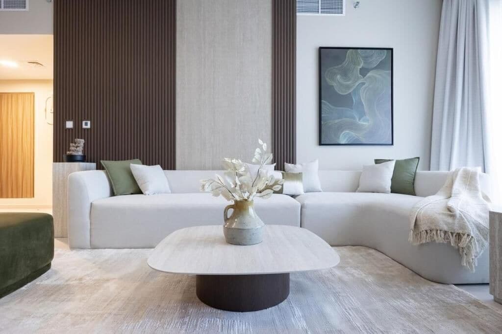 A modern living room with a sectional sofa, a round coffee table, and a vase with white flowers.