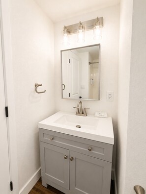 A bathroom with a white sink, a mirror, and a towel. - Charming Cottage 6 at Alhonna Resort (Lake Ozark)