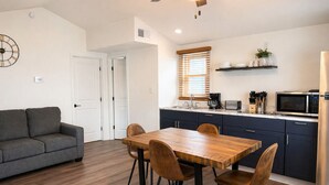 A compact living space with a dining area, kitchenette, and a sofa.