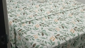 A bed with a floral bedspread, a bedside lamp, and a nightstand with a lamp. - Cozy 2-bedroom apartment located just 5 minutes from Nadi International Airport. (Martinar)