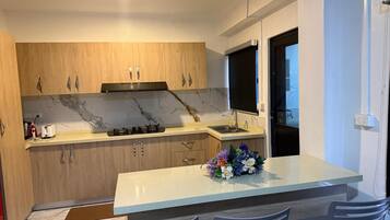Een moderne keuken met houten kastjes, een marmeren spatwand, een gasfornuis en een inbouwspoelbak.