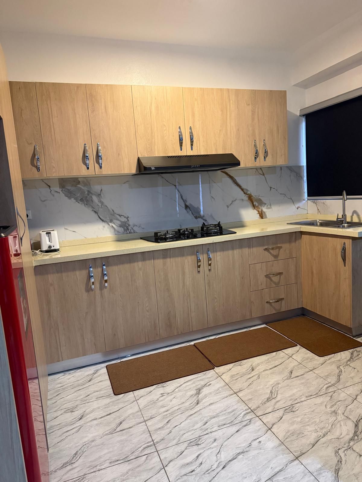Eine moderne Küche mit Holzschränken, einem Gasherd und einer Marmor-Spritzschutzwand.