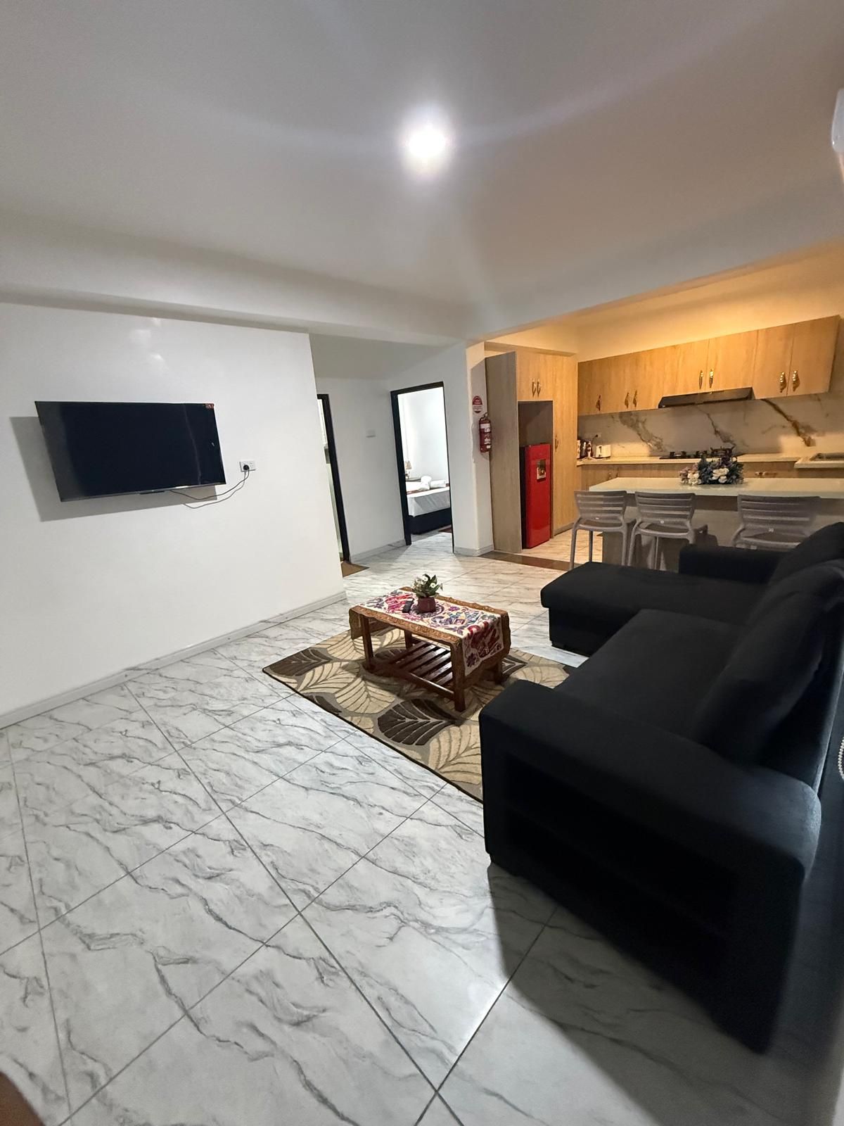 Een woonkamer met een flatscreen televisie, een bijzettafeltje en een bank.