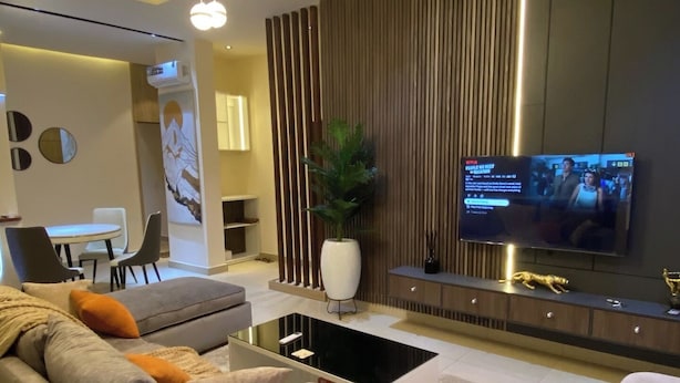 Una sala de estar moderna con sofá, mesa de centro, televisor y elementos decorativos.