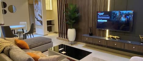 Una sala de estar moderna con sofá, mesa de centro, televisor y elementos decorativos.