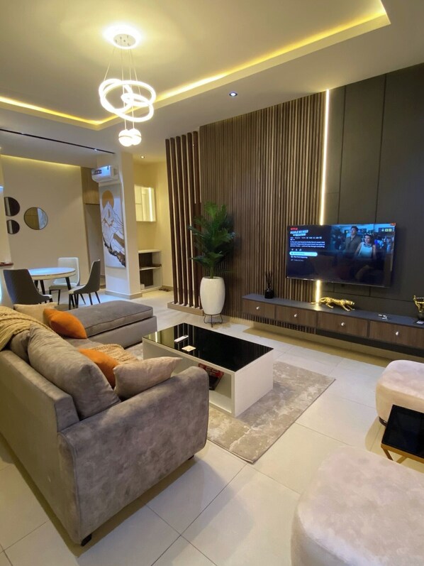 A modern living room with a sofa, coffee table, TV, and decorative elements. - Blueprint Apartment (Oba Ile)