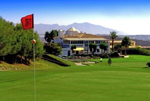 A golf course with a flag marked '81' and a building with a sign 'GOLF'. - SPECTACULAR FLAT WITH VIEWS OF THE SEA AND THE GOLF COURSE AT ISLAND DE RIVIERA (Riviera del Sol - Mijas Costa)