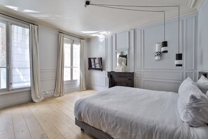 Un dormitorio con una cama grande, un aparador, un espejo y una ventana con cortinas.