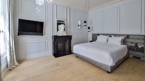 A bedroom with a large bed, a fireplace, a television, and a wall-mounted sculpture. - Villa Amore (Paris)