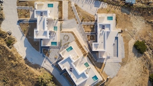 An aerial view of a modern resort with multiple buildings, each featuring a swimming pool and a patio area. - Parolea Luxury Living Hotel (Paros)
