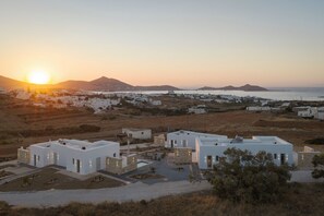 Un quartier résidentiel en bord de mer, avec des bâtiments modernes aux façades blanches, un ciel dégagé et un coucher de soleil sur la mer.
