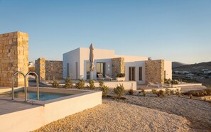 Une villa moderne dotée d’une piscine, de murs en pierre et offrant une vue sur la campagne.