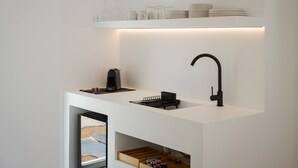 A modern kitchen with a white countertop, a black faucet, and a coffee machine. - Parolea Luxury Living Hotel (Paros)