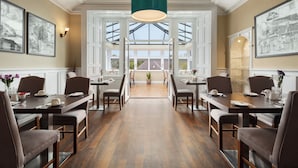 A dining area with multiple tables and chairs, large windows, and artwork on the walls. - Duchally Hotel & Country Estate (Auchterarder)