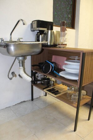 A kitchen with a sink, a coffee maker, a kettle, a toaster, and a shelf with dishes and glasses. - 2-Bedroom Apartment Steps from the Racetrack (Mexico City)