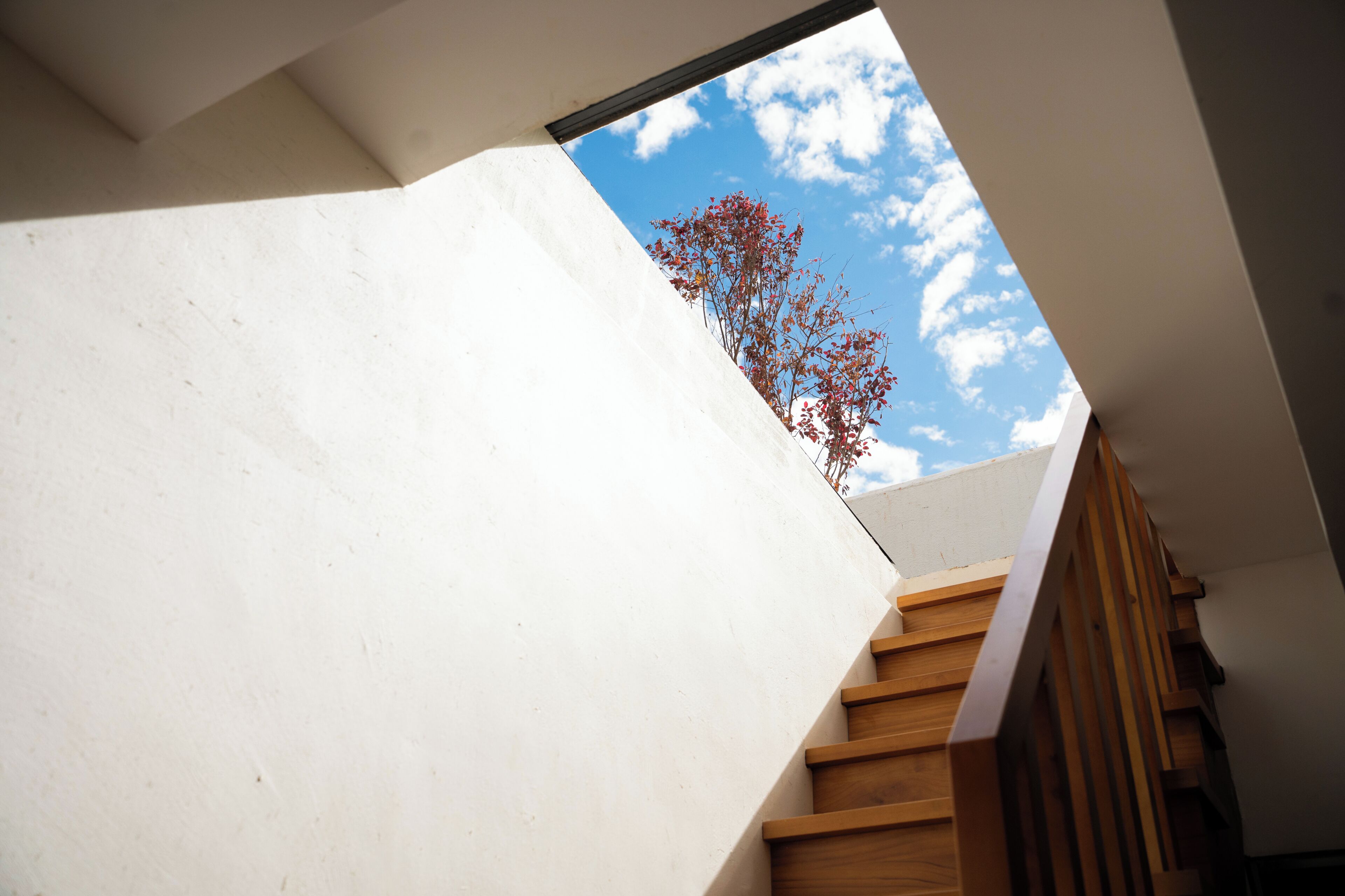 A modern staircase with wooden steps and a white wall.