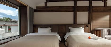 A hotel room with two beds, a large window, and a view of traditional buildings outside.