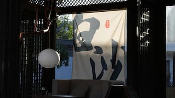 An outdoor seating area with tables and chairs, a hanging lantern, and a large banner with Japanese characters.