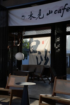 An outdoor seating area with tables and chairs, a hanging lantern, and a large banner with Japanese characters.