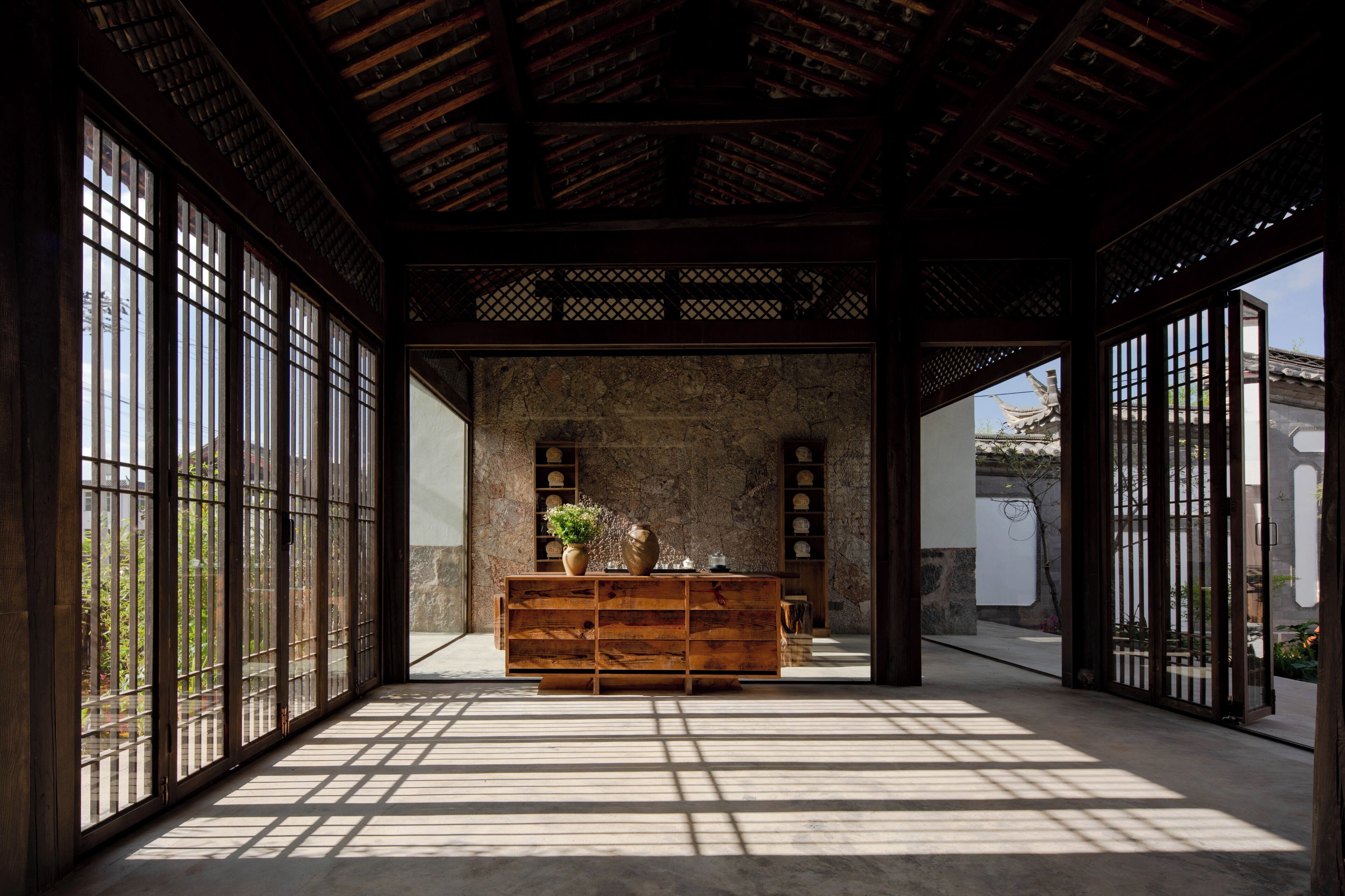 A traditional Japanese interior with tatami flooring, a wooden reception desk, and a stone wall.