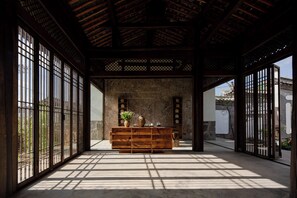 Un interior japonés tradicional con suelo de tatami, un mostrador de recepción de madera y una pared de piedra.