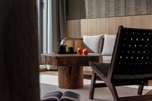 Una habitación moderna con una mesa redonda de madera, una silla negra y un sofá con cojines.