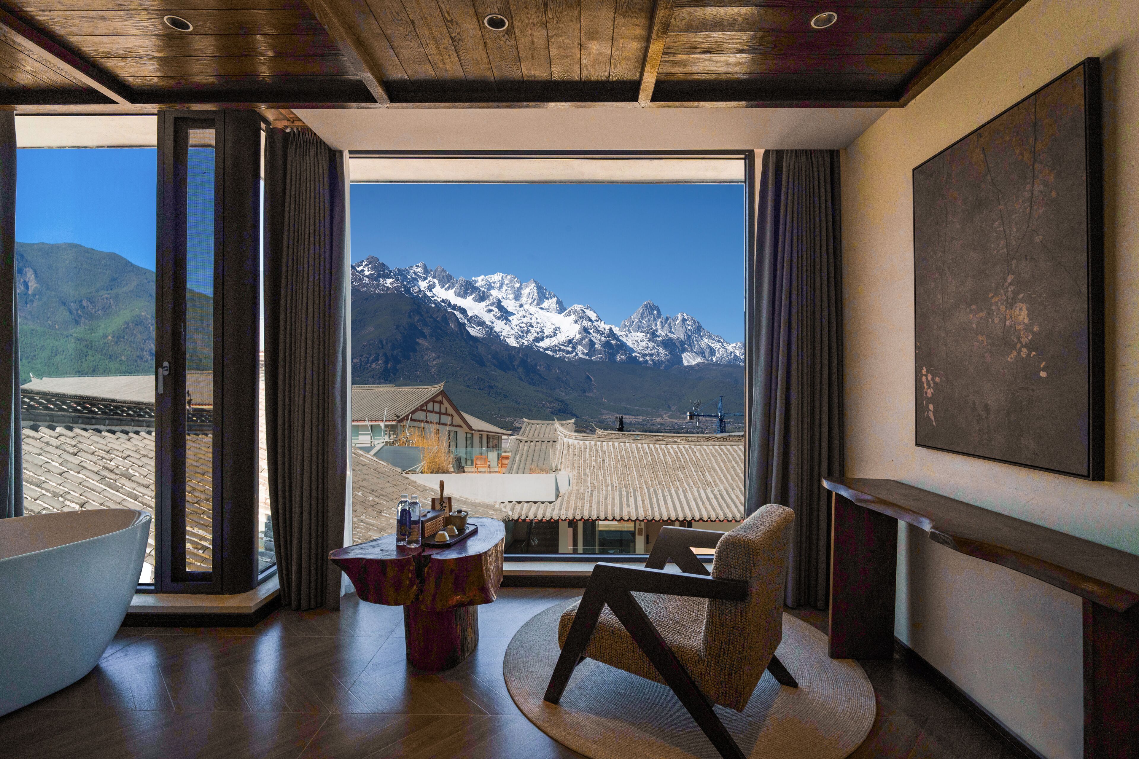 Habitación con un amplio ventanal que ofrece vistas a la montaña, techo de madera y una decoración interior moderna.