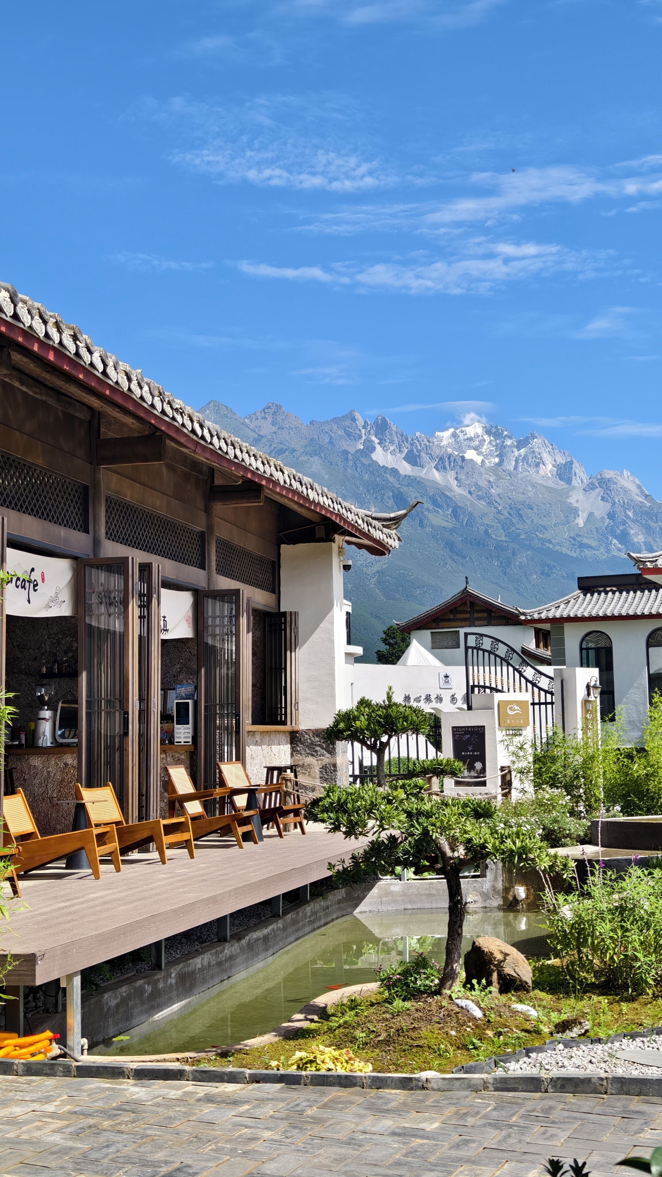 Un edificio tradicional con terraza, sillas de madera y una pequeña fuente.