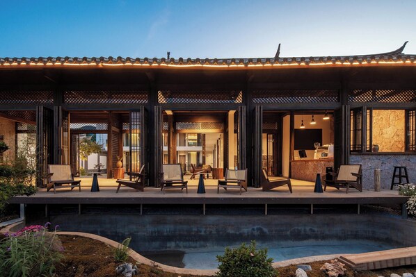A modern building with a pool, outdoor seating, and traditional architectural elements.