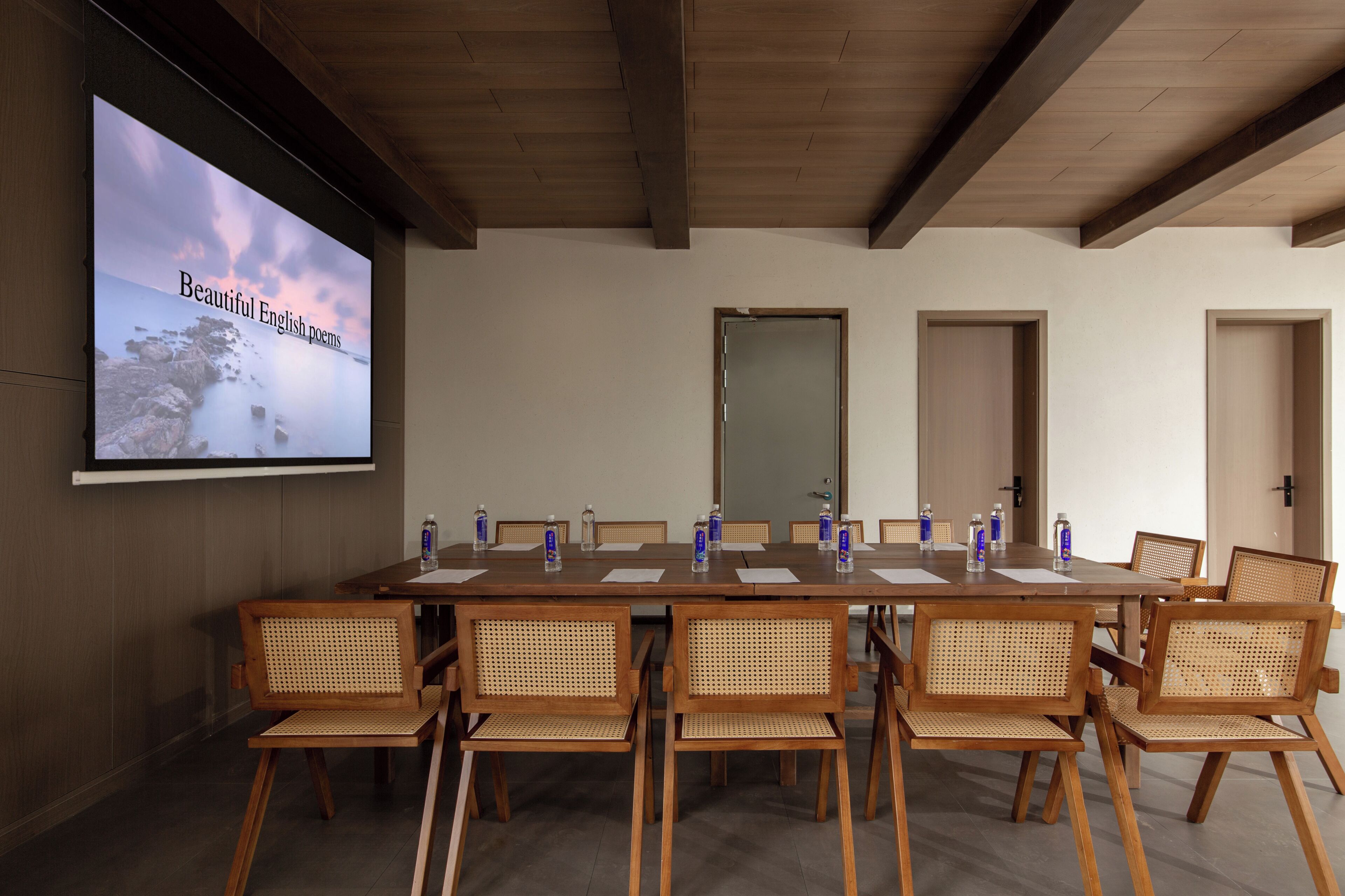 A conference room with a long table, chairs, a projector screen, and doors.