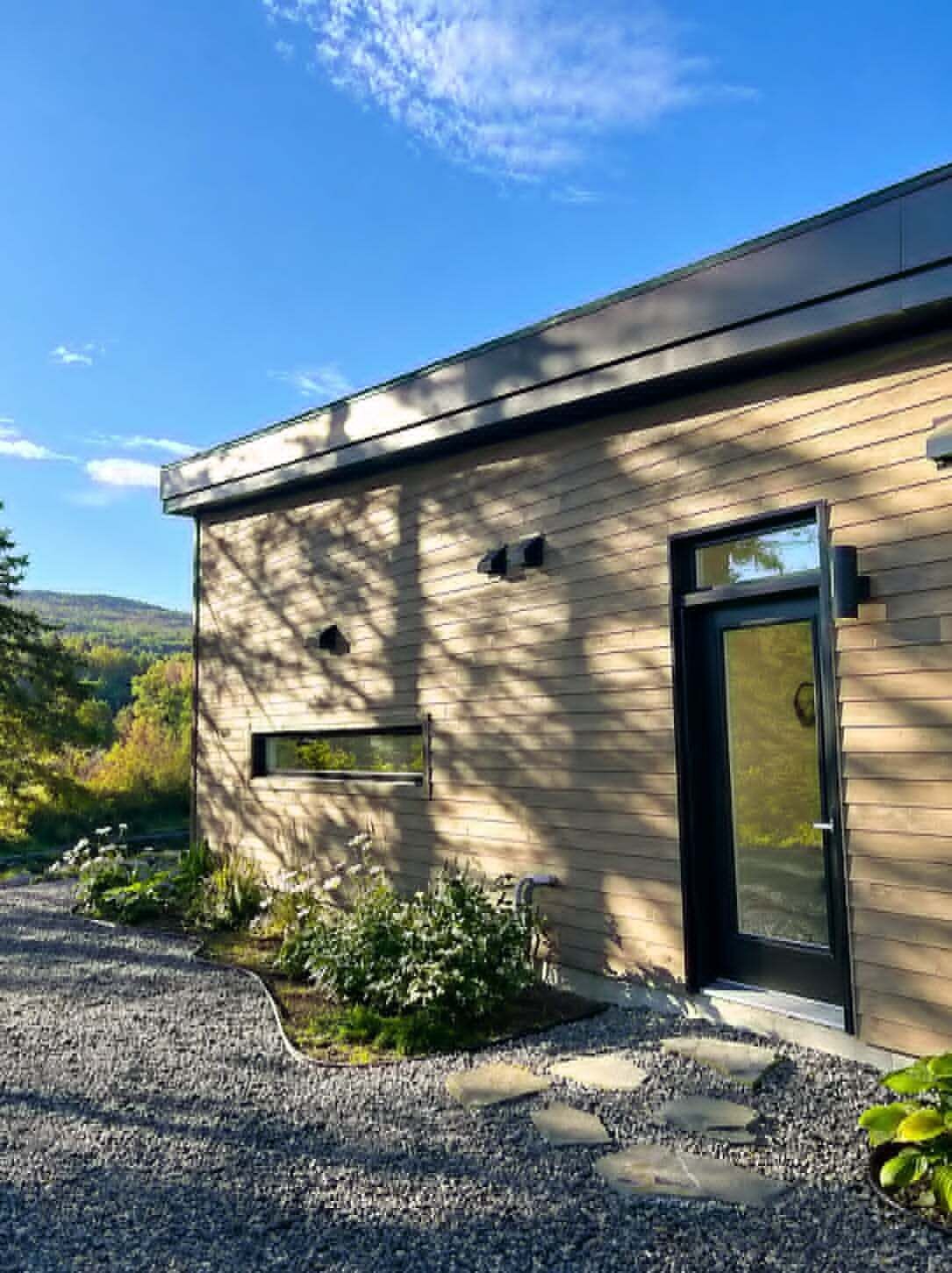 Un bâtiment moderne doté d’un toit plat, d’une porte noire et d’une fenêtre.