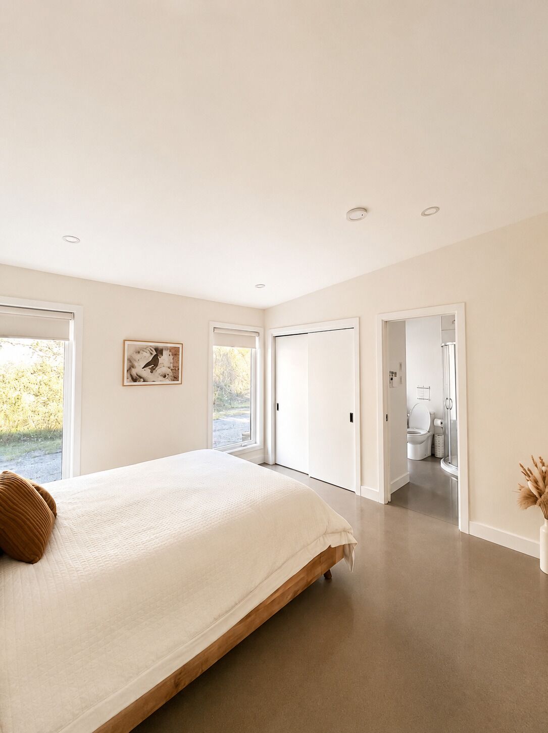 Une chambre à coucher avec un grand lit, un tableau accroché au mur et une vue sur la salle de bain par une porte ouverte.
