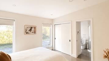 Une chambre à coucher avec un grand lit, un tableau accroché au mur et une vue sur la salle de bain par une porte ouverte.