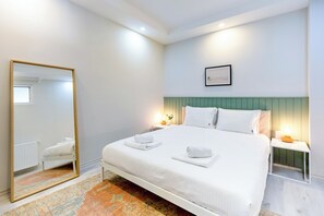 Ein Hotelzimmer mit einem großen Bett, einem Nachttisch, einem Spiegel und einem gerahmten Bild an der Wand.