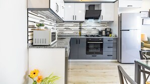 Eine moderne Küche mit weißen Schränken, einem Backofen und einer Mikrowelle.