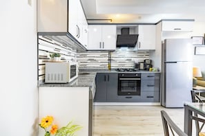 Eine moderne Küche mit weißen Schränken, einem Backofen und einer Mikrowelle.