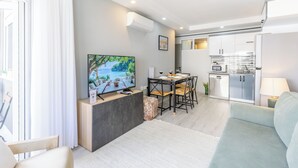 Ein modernes Wohnzimmer mit Flachbildfernseher, Esstisch und einer Sitzecke.