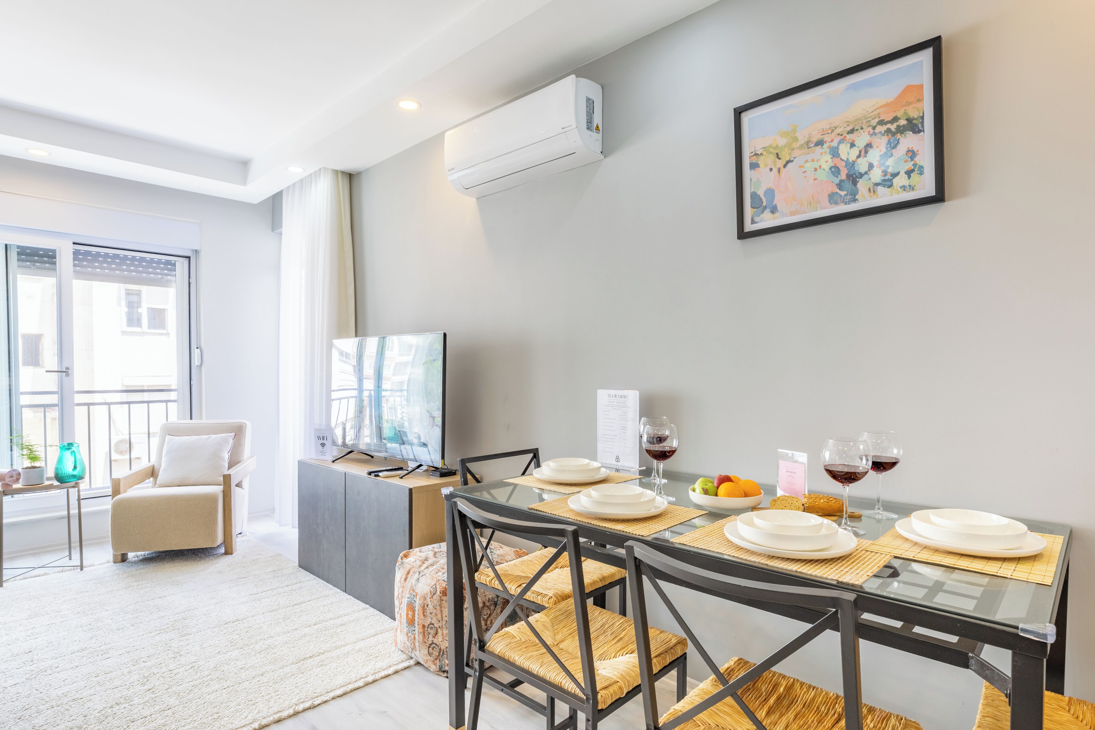 A modern dining area with a glass table, chairs, and a television.