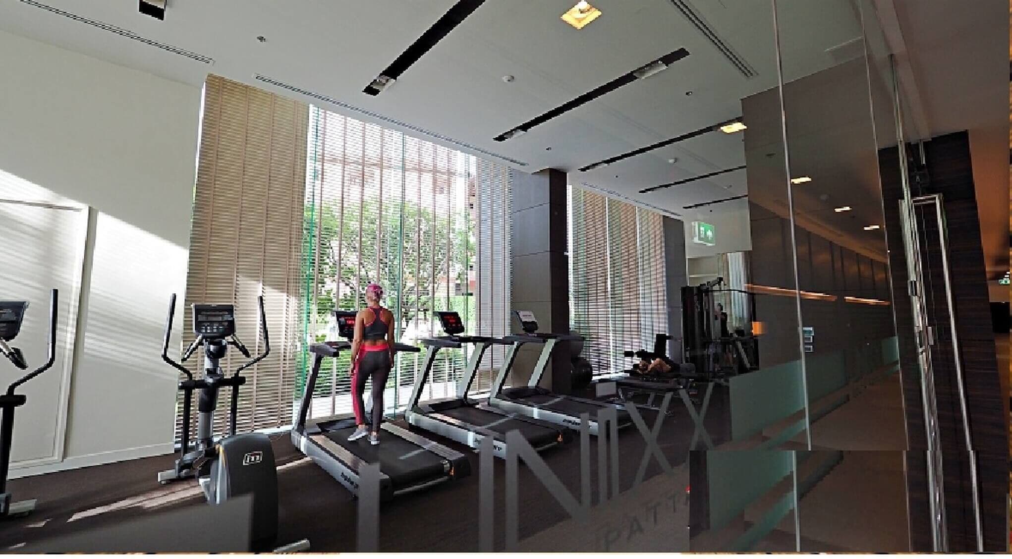 Une salle de sport moderne équipée de tapis de course, de vélos d’appartement et d’appareils de musculation.