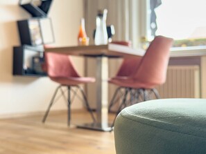 A modern dining area with a table and chairs, a radiator, and a window. - Mountain-View Terrace & aktivCARD included - Getaway for two (Bodenmais)