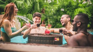 En grupp människor i en swimmingpool, med drycker och en korg.