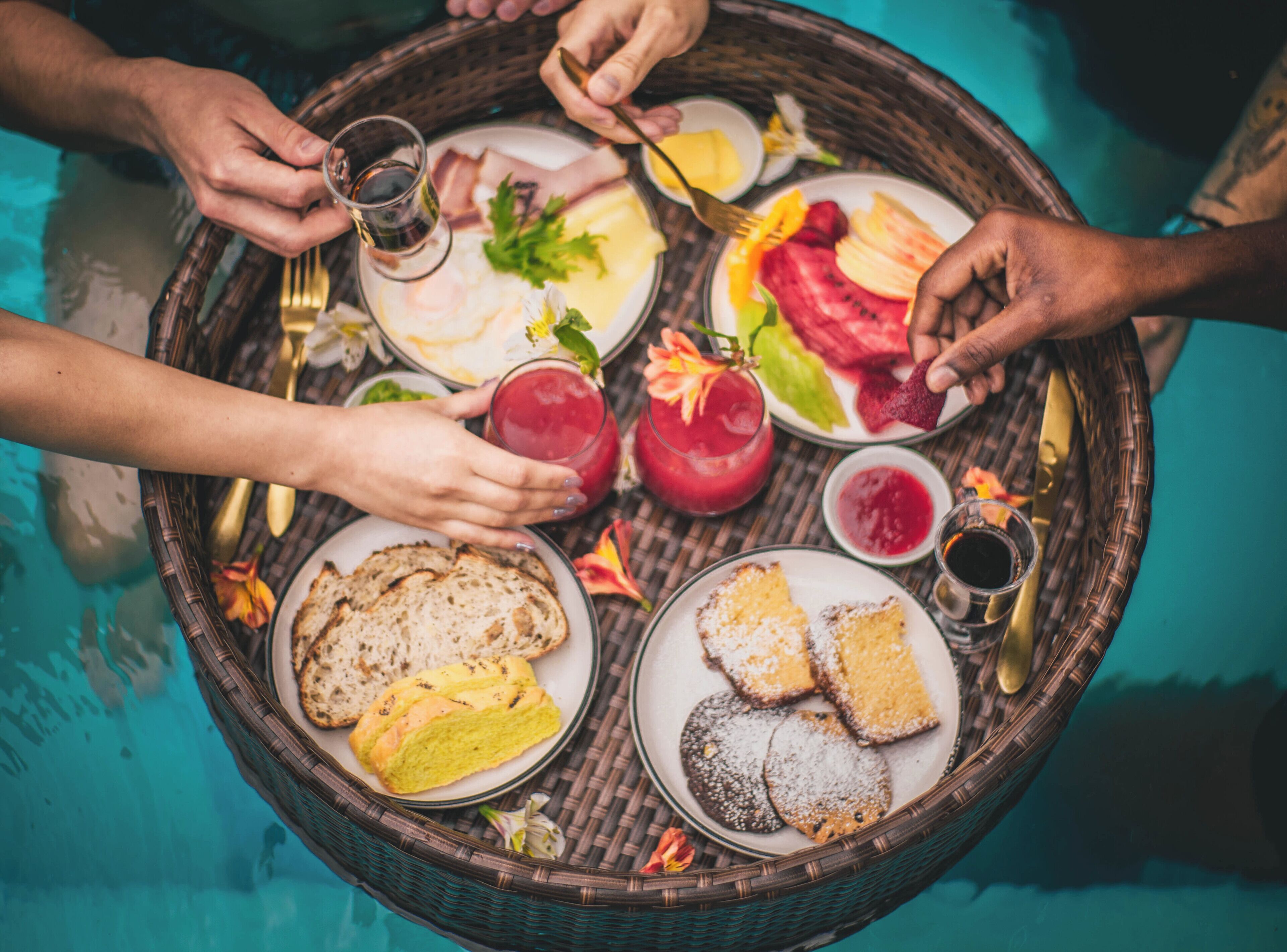 Una mesa redonda con diferentes alimentos y bebidas, rodeada de gente.
