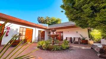 Un patio con una fuente, plantas en macetas y asientos al aire libre.