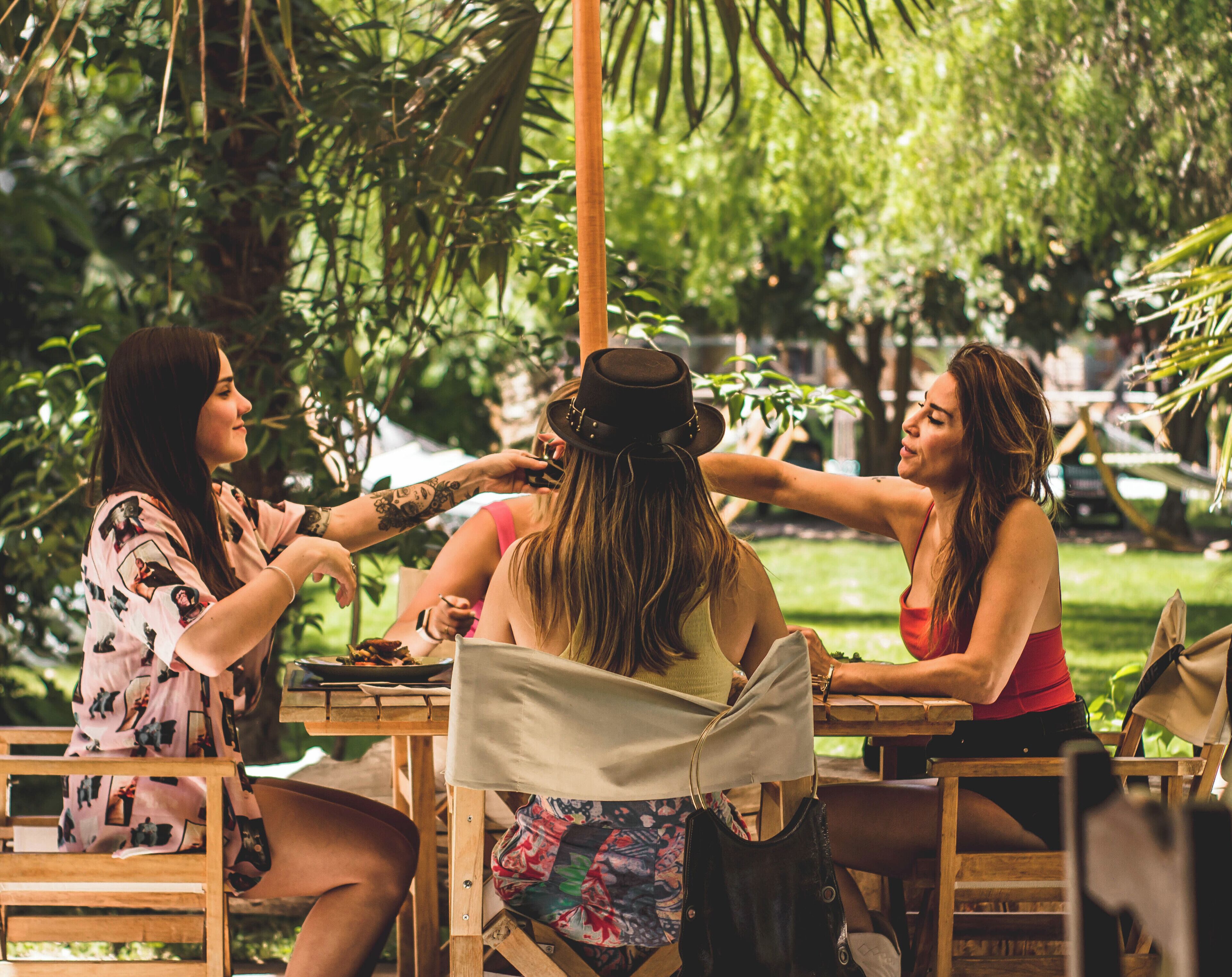 A group of people seated at an outdoor table with a natural backdrop.