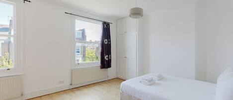 Une chambre à coucher avec un lit, une fenêtre, un radiateur et une porte.