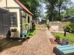 A brick pathway leading to a house with a wooden fence, potted plants, and outdoor furniture. - Cozy 1-bedroom apartment in quintessential Forest Hill neighborhood (Richmond)