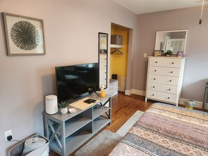 A living room with a television, a white dresser, a mirror, and a patterned rug. - Cozy 1-bedroom apartment in quintessential Forest Hill neighborhood (Richmond)