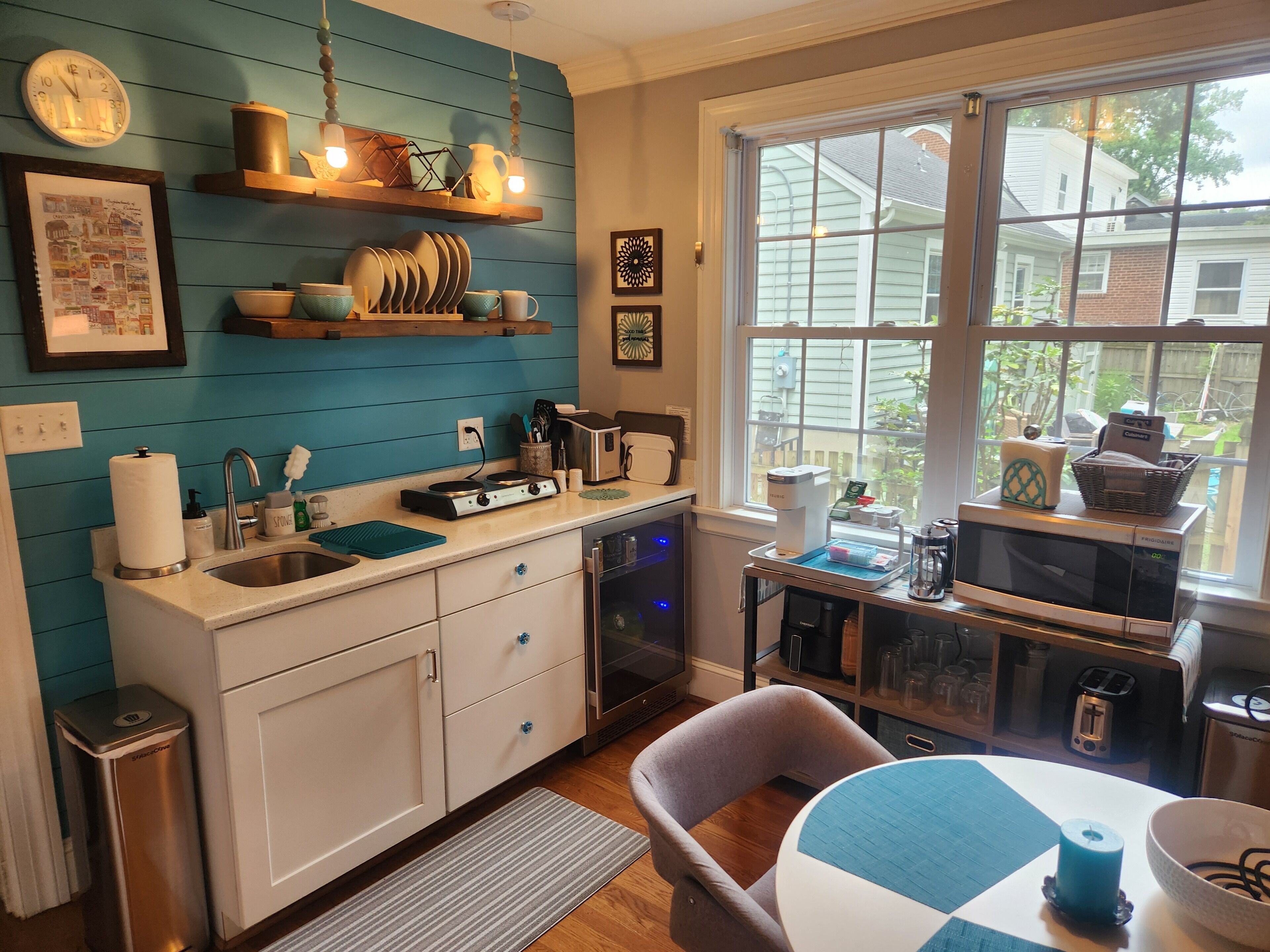 A kitchen with a window, a sink, a stove, and a dining area with a table and chairs.