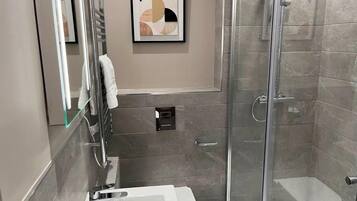 A modern bathroom with a glass shower enclosure, a white sink, and a framed abstract artwork on the wall.