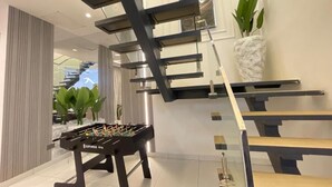 Un interior moderno con mesa de fútbol, una escalera y una planta en maceta.